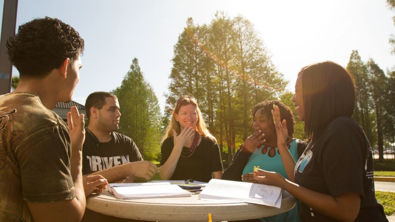 Students sitting outside on campus together. 