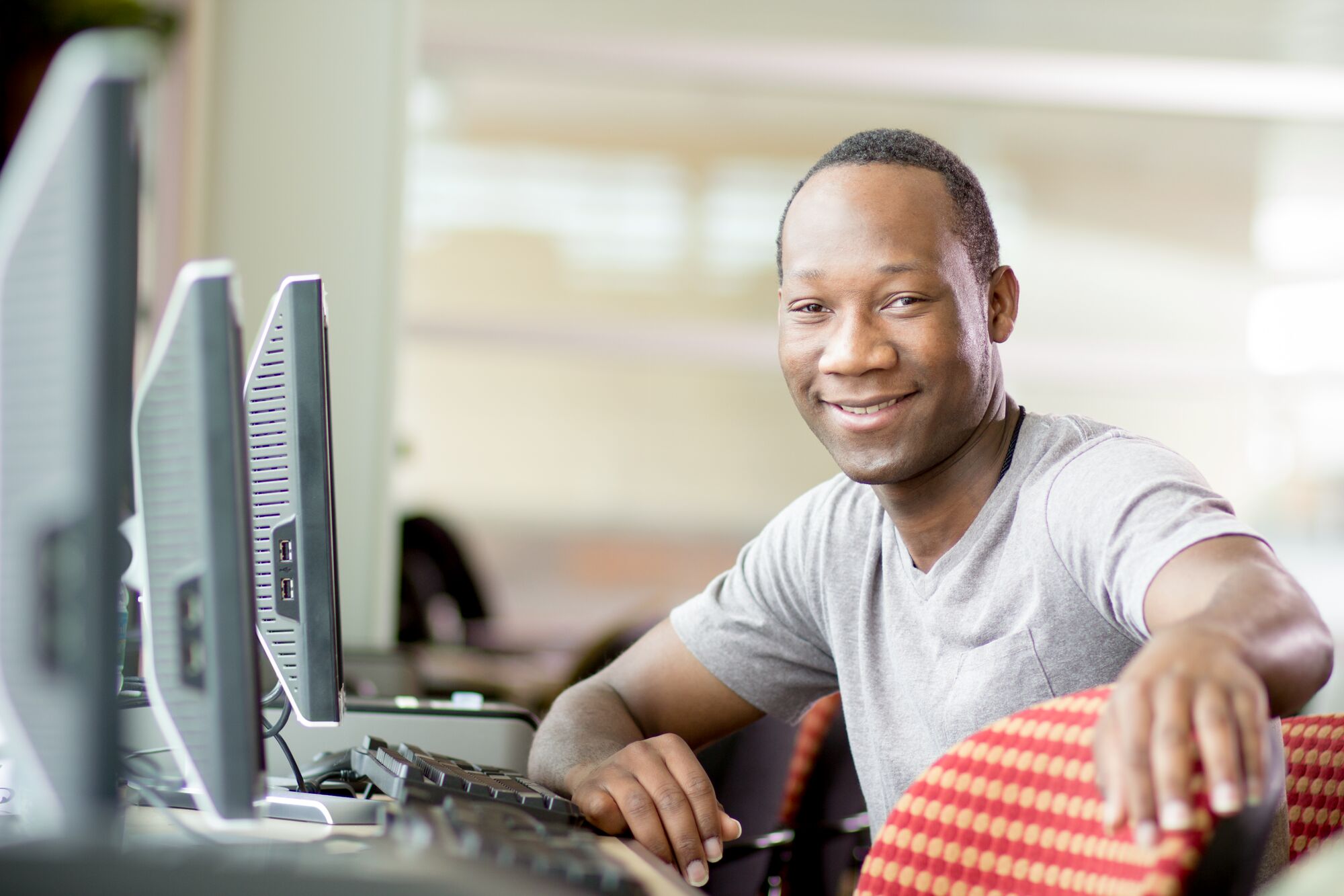 student sitting in computer lab smiling at camera