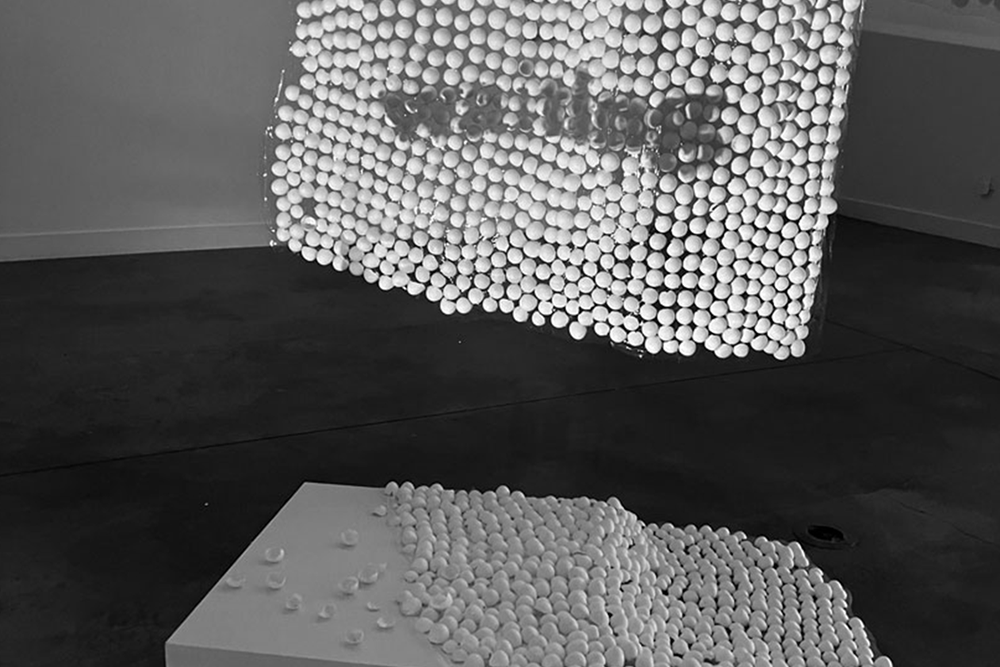 Black and white photograph featuring a sculpture crafted from an array of white balls, highlighting its unique design