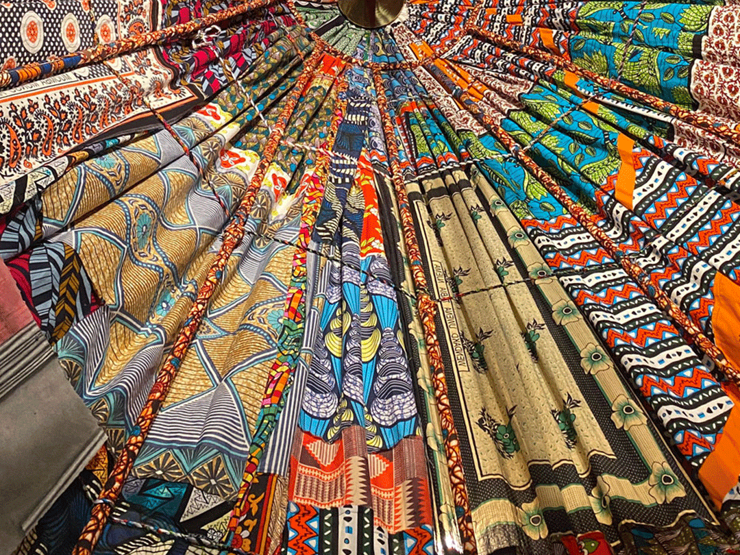 A vibrant display of various colorful, patterned fabrics arranged in a circular pattern, viewed from below