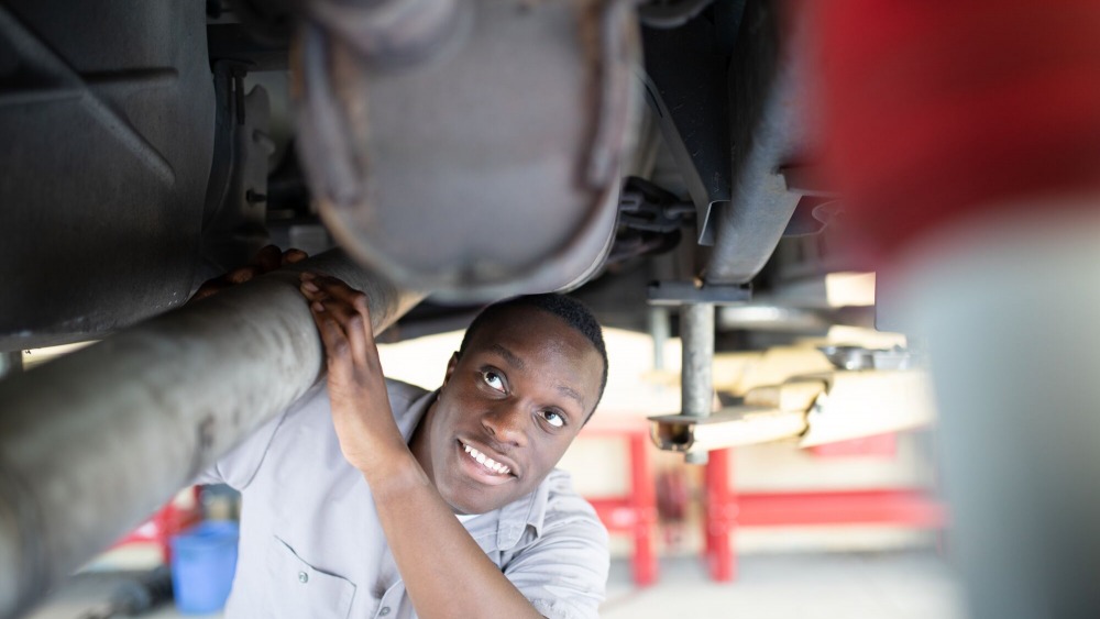 African American male auto tech student looking at a vehicle.
