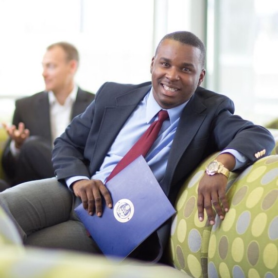 Man in business suit sitting casually on a couch with other business professionals