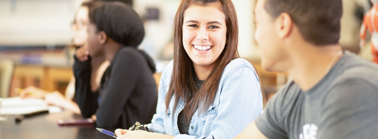 Smiling white student in classroom among other classmates during a lecture