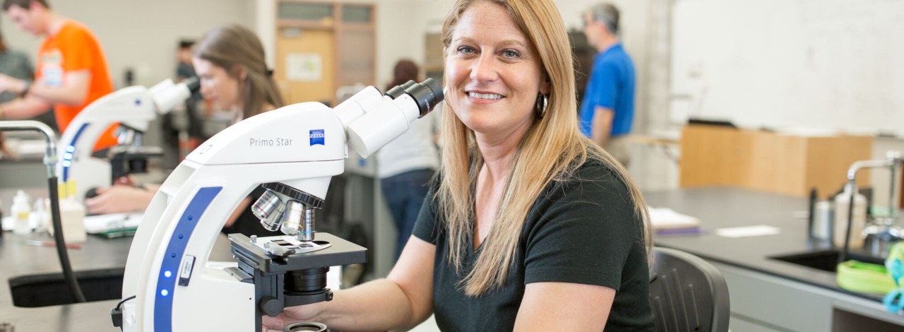 Female student using a microscope in a lab room