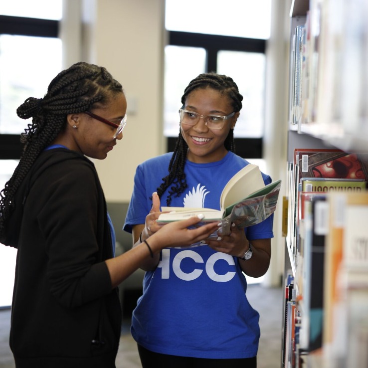 Two students looking at books in the library